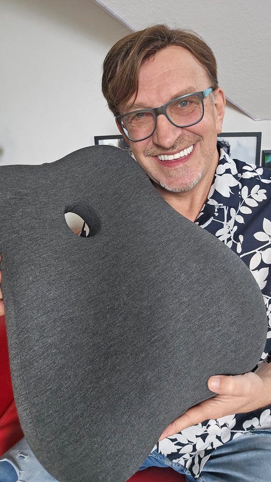 Benutzer hält das ErgoSupport Rückenkissen, ergonomisches Design für bequeme und gesunde Sitzhaltung.